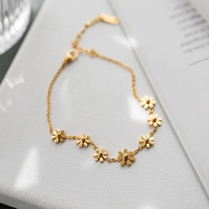 Elegante goldene Gänseblümchen-Halskette mit sieben Blumenanhängern auf weißem Grund