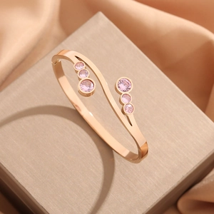 Eleganter roségoldener Titan-Wellenarmreif mit rosa Zirkonia auf Satinhintergrund