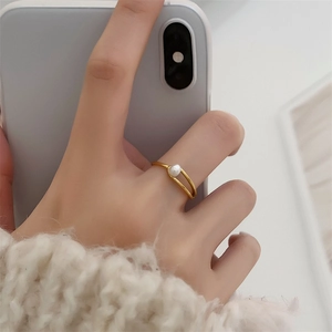 Détail d'une bague géométrique plaquée or 18K avec perle blanche sur mannequin