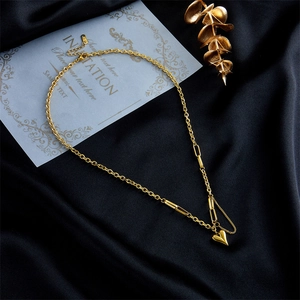Dettaglio di una collana vintage con ciondolo a cuore dorato su seta nera elegante.