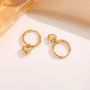 Polished gold heart drop earrings on silk fabric with elegant minimalist style