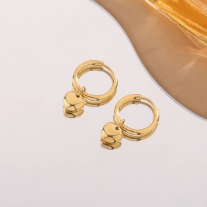 Elegant gold heart hoop earrings with a polished finish reflecting on a mirror surface