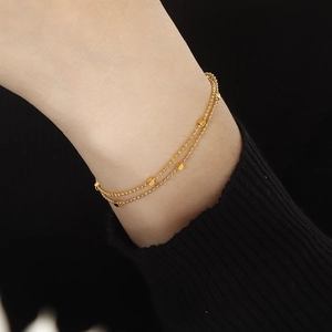 Bracelet double couche en perles dorées avec petits cubes élégants sur poignet femme