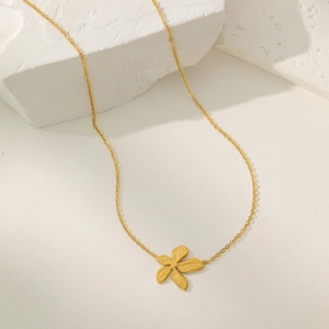 Collier fleur en acier inoxydable plaqué or 18 carats avec pétales texturés sur support blanc