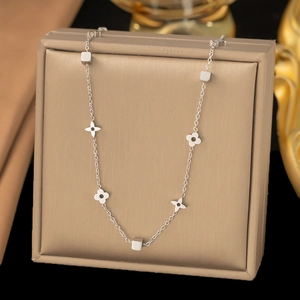 Close-up of silver steel necklace featuring hollow clover and geometric cube charms