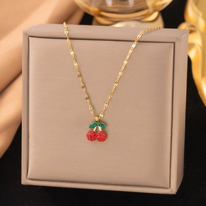 Détail d'un pendentif cerise étincelant avec feuilles vertes sur collier en or