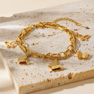 Double-layered 18k gold butterfly bracelet with matte finish charms on stone background