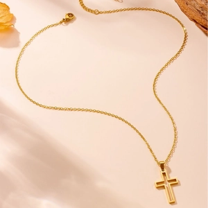 Polished stainless steel gold necklace with hollow cross pendant on warm aesthetic background