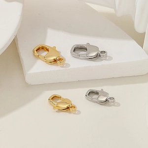 Macro shot of 18k gold-plated and silver lobster claw clasps on white geometric stones