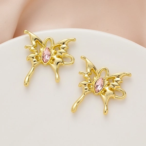 Detailed macro view of gold butterfly pendant with pink stone on pink silk fabric