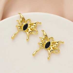 Golden butterfly charms with black stone inlay on elegant white and pink satin backdrop