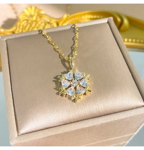 Nahaufnahme des blauen herzförmigen Kristall-Schneeflocken-Anhängers an goldener Kette