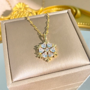 Elegante goldene Schneeflocken-Halskette mit Herz-Kristallen auf einer Schmuckbox