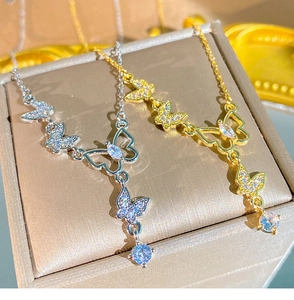 Gros plan de colliers pendentifs papillon en or et argent avec pavé de cristaux brillants