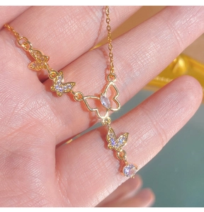 Détail du collier papillon doré avec cristaux violets présenté au creux de la main