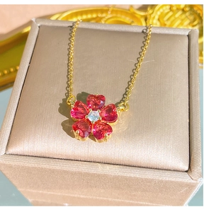 Dettaglio della collana fiore di ciliegio con petali a cuore rossi e catena oro