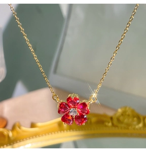 Dettaglio del ciondolo a fiore con petali di zircone rosso a cuore e catena d'oro