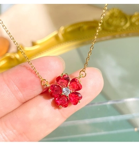 Dettaglio ravvicinato del ciondolo a fiore in granato a cuore con zirconi e finitura dorata