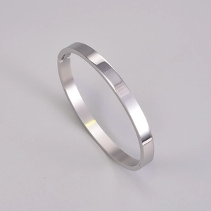 Detailed macro view of mirror-polished silver titanium steel bangle with side hinge clasp