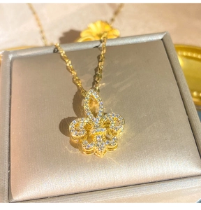 Dettaglio di un ciondolo a giglio dorato con zirconi incastonati su una scatola regalo