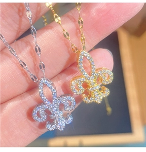Dettaglio di ciondoli a giglio in argento e oro con zirconi brillanti incastonati