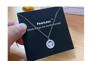 Close-up of silver heart necklace with sparkling diamonds on brand display card