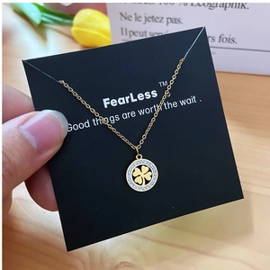 Close-up of gold-plated clover pendant with pavé rhinestones on a warm wooden surface
