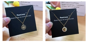 Close-up of gold plated tree of life and interlocking heart pendants on branded display card
