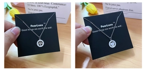 Detail of silver tree of life and pavé heart necklaces on branded display cards