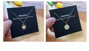 Detail of luxury gold necklaces with heart and clover pendants on branded cards
