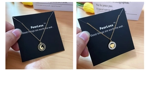 Detail of gold pendant necklaces featuring hollow moon star and heart designs on a black card
