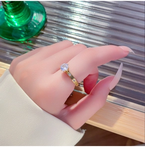 Macro detail of gold six-prong diamond ring featuring a sparkling zircon crown and pave band