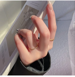 Detailopname van twee dunne gouden titanium ringen met kleine kristallen aan een hand