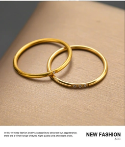 Detail van twee gestapelde gouden minimalistische ringen met enkele en drievoudige zirkoon