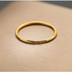 Close-up van minimalistische gouden titanium ring met drie ingelegde zirkonia stenen