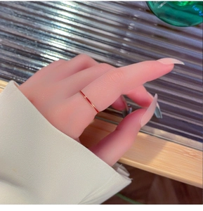 Detalle macro de un anillo fino de esmalte rojo minimalista en el dedo de una modelo