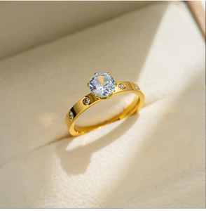 Close-up of a gold-plated titanium ring with round cubic zirconia in a six-prong setting