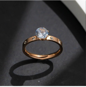 Close-up of rose gold ring featuring a round center stone and diamond-encrusted band