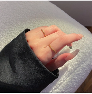 Detail van minimalistische goud vergulde titanium ringen met een diamant op hand