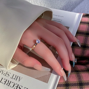 Elegant gold-tone titanium steel ring with sparkling round zircon, worn on hand over magazine