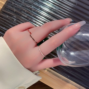 Tres anillos minimalistas de acero de titanio en oro, rojo y blanco en los dedos de modelo