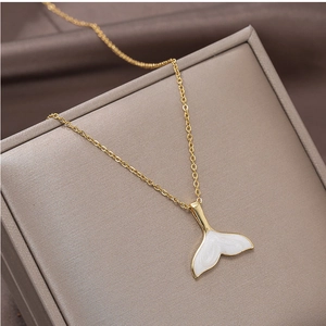 Close-up of golden fishtail pendant necklace with white enamel inlay on a jewelry box