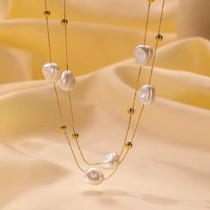 Double-layered gold titanium necklace with baroque pearls and beads on silk background