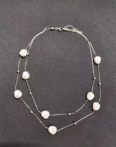 Dettaglio di una catena d'argento a doppio strato con perle barocche e sfere