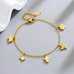 Detailansicht goldener Fußkettchen mit Kleeblatt, Elefant und Hamsa-Hand Anhängern