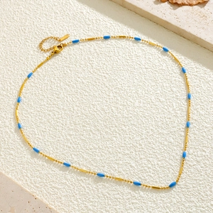 Detailed macro view of gold-plated stainless steel necklace with blue beads and clasp