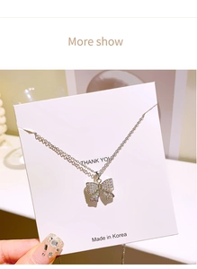 Détail du collier noeud argenté serti de strass sur une carte de présentation