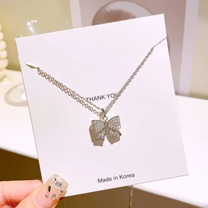 Collier à pendentif nœud argenté élégant avec strass étincelants sur carte cadeau