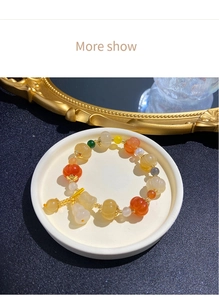 Detail of beaded gemstone bracelet with pumpkin-shaped beads and white gourd charm