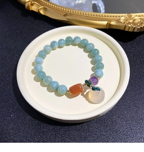 Detail of natural gemstone bracelet with blue beads and a white jade-like pendant